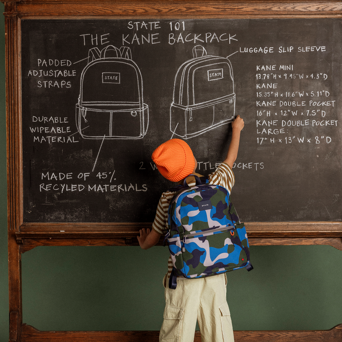 boy writing on chalkboard wearing Kane Kids camo