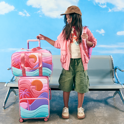 Girl sitting at airport with state bags rockaway duffle sunset and logan carry-on sunset