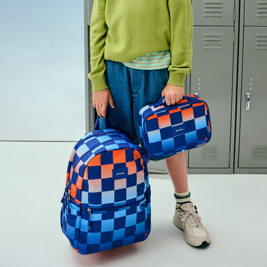boy standing holding kane double pocket backpack blue checkerboard