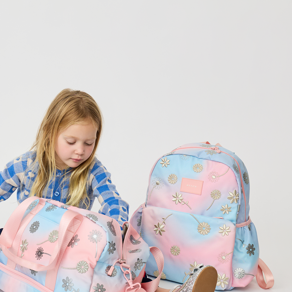 girl sitting with Wren Weekender and Kane Backpack Dreamy FLoral